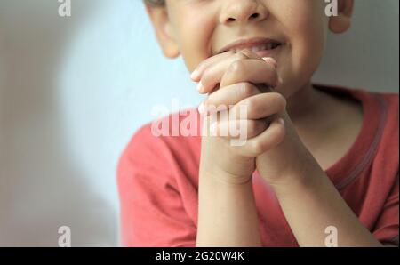 boy praying to God with hands held together with closed eyes on white background stock photo Stock Photo