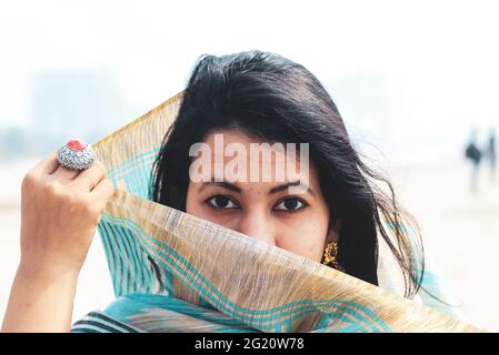 Young Indian woman portrait in sari with her face covered. Beautiful Indian Muslim woman covers her face with saree. Stock Photo