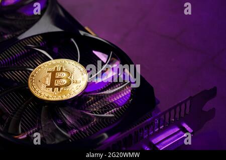 On the fans of a powerful video card, the coins of the Bitcoin cryptocurrency with a red backlight are displayed.The concept of mining and mining of c Stock Photo