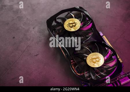 On the fans of a powerful video card, the coins of the Bitcoin cryptocurrency with a red backlight are displayed.The concept of mining and mining of c Stock Photo