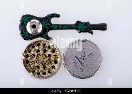 Cannabis pipe with hemp leaves drawings on it and a grinder with cannabis in it  Stock Photo