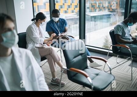Portrait of two doctors wearing masks while looking at digital tablet in conference Stock Photo