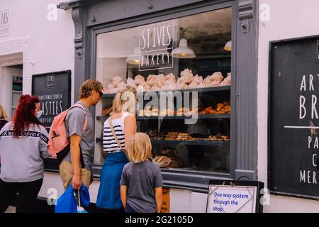 Customers looking in Cornish bakery window at St. Ives Bakery, Fore Street, St. Ives, Cornwall, UK, June 2021 Stock Photo