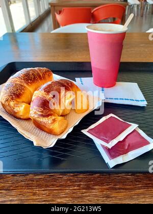 sweet fresh croissants (medialunas) on a tray on a wooden table.