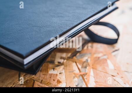 Detail of the sheets of paper of black leather photo album on a table with vintage wood background. Wedding or family photo book memories. Family valu Stock Photo