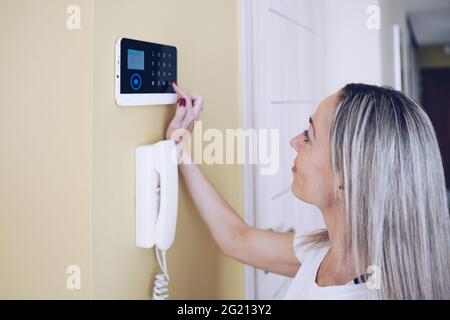 Woman pressing buttons on control panel for disarming smart home system. Stock Photo
