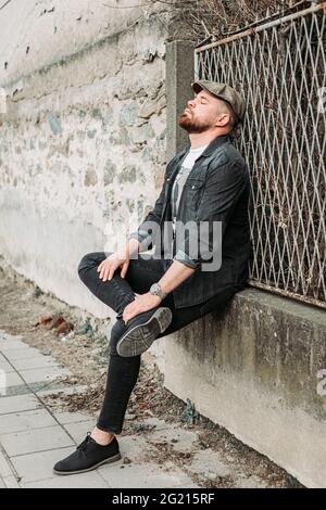 Portrait of a handsome guy with ivy hat leaning on the fence Stock Photo