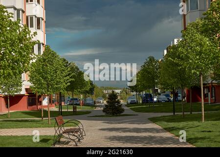 Kyiv,Ukraine - May 15 : Residential modern high-rise buildings, people walking along the street and car parking . Urban view on a bright sunny day with clouds. Stock Photo
