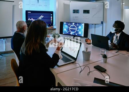A group of people sitting at a desk with a laptop Stock Photo