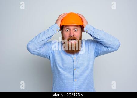 Isolated amazed architect with beard and orange helmet Stock Photo