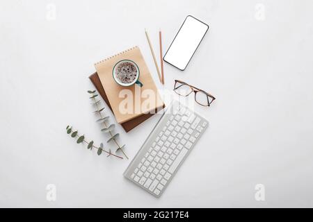 Mobile phone mockup on modern workspace desk. Empty phone screen mock up copy space with computer keyboard and office supplies. Flat lay Stock Photo