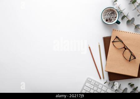 Glasses keyboard coffee cup notebook office supplies on desk top view. Modern desk workspace with copy space on white background Stock Photo
