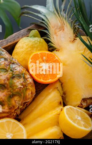 Ripe pineapple. Tropical fruits Mix wooden box. Tangerines oranges pineapples lemons. Sliced tropical citrus vitamin dessert as summer background Stock Photo