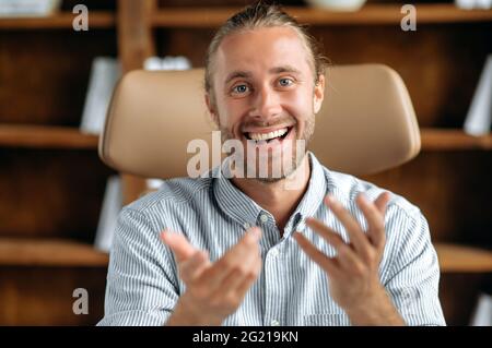 Friendly smart confident caucasian businessman or tutor, communicating with colleagues or client on conference call, looking at camera, gesturing with his hands, smiles pleasantly Stock Photo