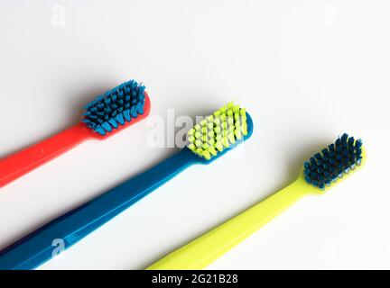 Set of plastic multicolored toothbrushes - green, blue, red - isolated on a white background. Bright colorful soft toothbrushes with multicolored shie Stock Photo