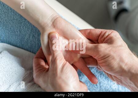 Close up on hands of unknown caucasian man therapist massaging and stretching hands of unknown woman female client Stock Photo