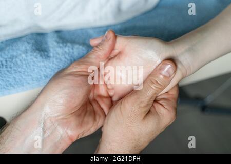 Close up on hands of unknown caucasian man therapist massaging and stretching hands of unknown woman female client Stock Photo