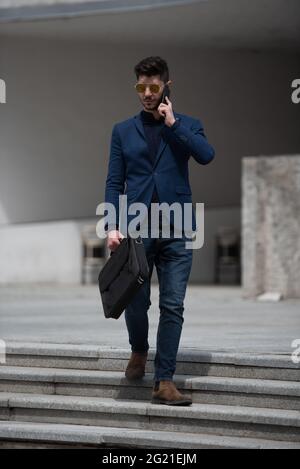 Urban businessman is going down the stairs while thinking and talking about the business plan Stock Photo