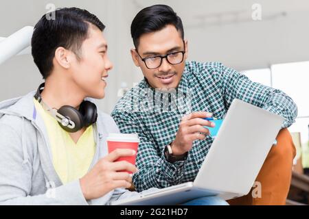 Experienced employee explaining to his colleague business information displayed on laptop in a modern office Stock Photo
