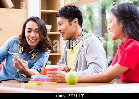 Successful professional team of web designers smiling while testing responsive layout on both mobile phone and desktop PC Stock Photo