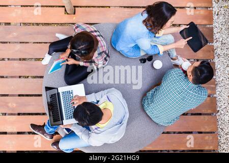 High angle view of four young employees using modern wireless technology while working outdoors on different projects Stock Photo