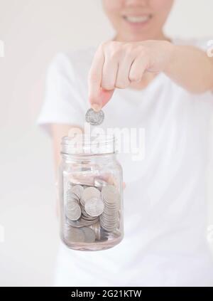 business, finance, saving, banking and people concept - close up of woman hands putting us dollar money into glass mason jar Stock Photo