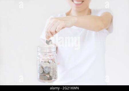 business, finance, saving, banking and people concept - close up of woman hands putting us dollar money into glass mason jar Stock Photo