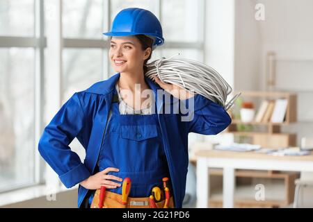Beautiful female electrician with cables in room Stock Photo