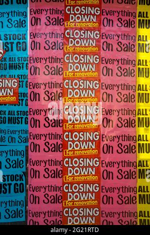 Shop window with brightly coloured closing down and sale signs. Stock Photo