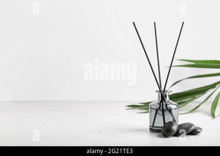 Reed diffuser with tropical leaf and spa stones on white background ...