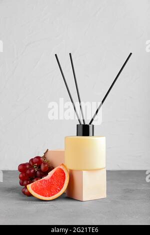 Reed diffuser with fruits on table against light background Stock Photo