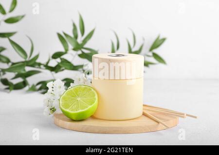Reed diffuser with lime and flowers on light background Stock Photo