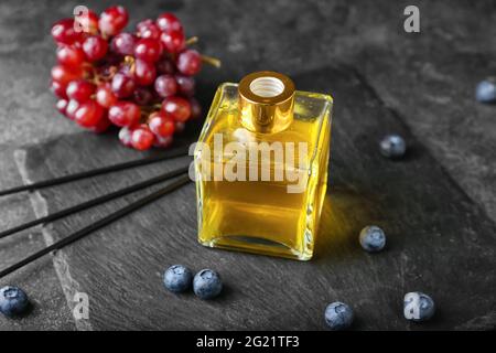 Reed diffuser with grapes and blueberries on dark background Stock Photo