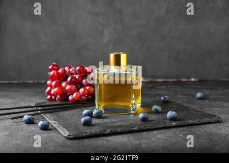 Reed diffuser with grapes and blueberries on dark background Stock Photo
