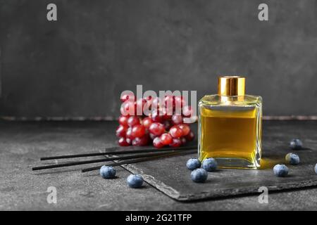 Reed diffuser with grapes and blueberries on dark background Stock Photo