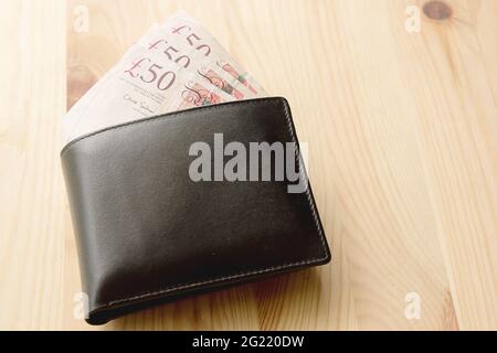Leather brown men's wallet in a man's hand on a vintage wooden background  Stock Photo - Alamy