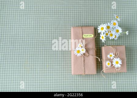 Gift box wrapped with brown craft paper and decorated with natural chamomile flowers with words of gratitude. Top view, flat lay, place for text. High Stock Photo