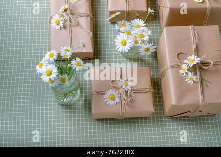 Set of gifts box wrapped with brown craft paper and decorated with natural chamomile flowers. Top view, flat lay, place for text. High quality photo Stock Photo