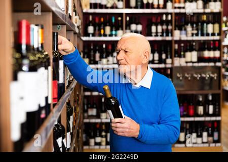 Mature man chooses red wine Stock Photo