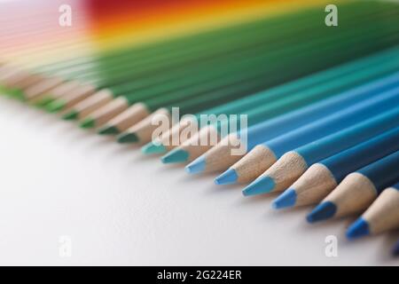 Many multi-colored pencils lying in colors of rainbow on white background Stock Photo