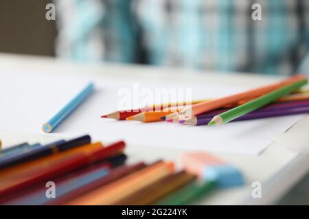 Many multi-colored pencils lying on blank sheet of paper closeup Stock Photo