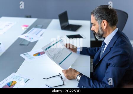 Elegant mature businessman analyzing data in office Stock Photo