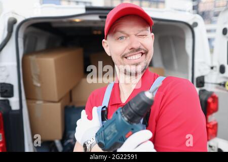 Master repairman holding electric drill in his hands near car Stock Photo