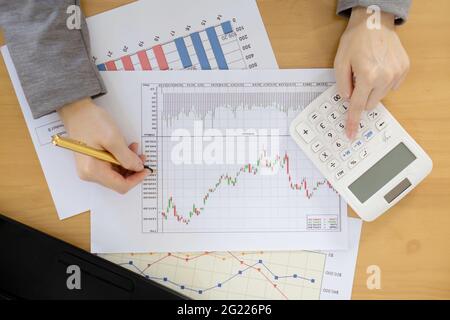 Businesswoman using calculator while analyzing graphs Stock Photo