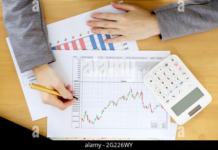 Businesswoman using calculator while analyzing graphs Stock Photo