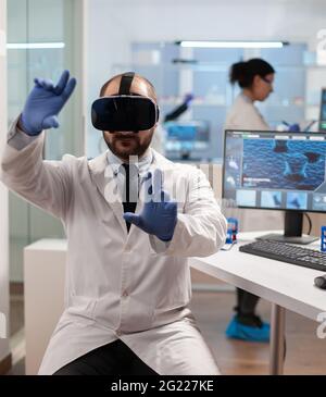 Professional scientist using medical inovation in lab wearing virtual reality glasses. Team of researchers working with equipment device, future, medicine, healthcare, professional, vision, simulator. Stock Photo