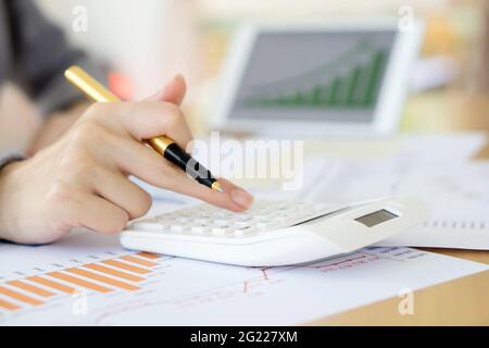Close-up Of Businesswoman Analyzing Financial Report With Calculator At Wooden Stock Photo