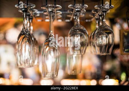 Selective focus of clean empty wine glasses hanging in bar counter. Stock Photo
