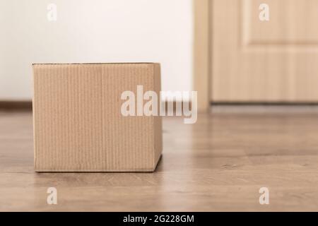 Delivered Cardboard Box Lying On Floor Near Door Of Apartment Stock Photo