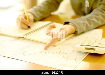 Young Businesswoman Analyzing Report On Chart With Calculator Stock Photo